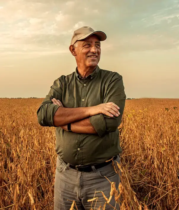 Confident farmer with arms crossed smiling in a harvested crop field - connect with drone spraying services through American Drone Network