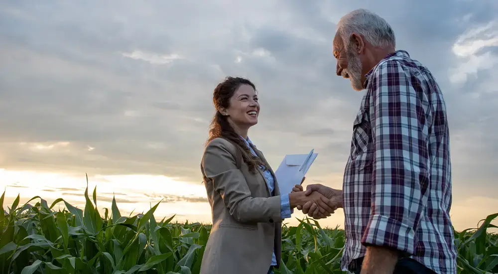 Drone service provider and farmer shaking hands in a cornfield, representing ADN partner relationships